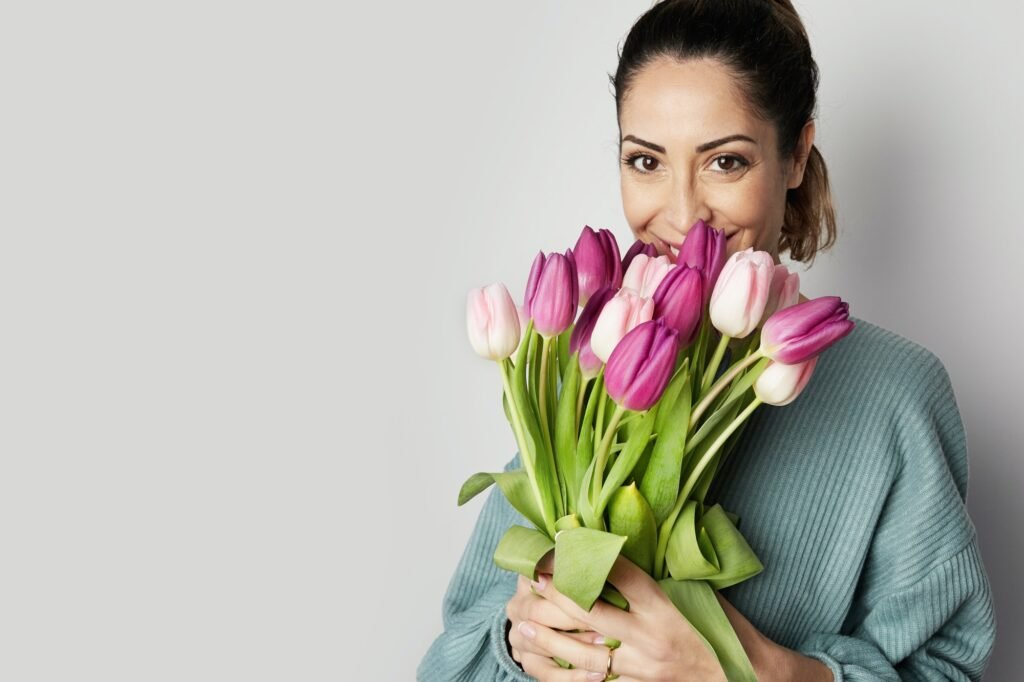 portrait-of-a-cheerful-young-woman-holding-colorful-tulips-bouquet-isolated-over-gray-background.jpg